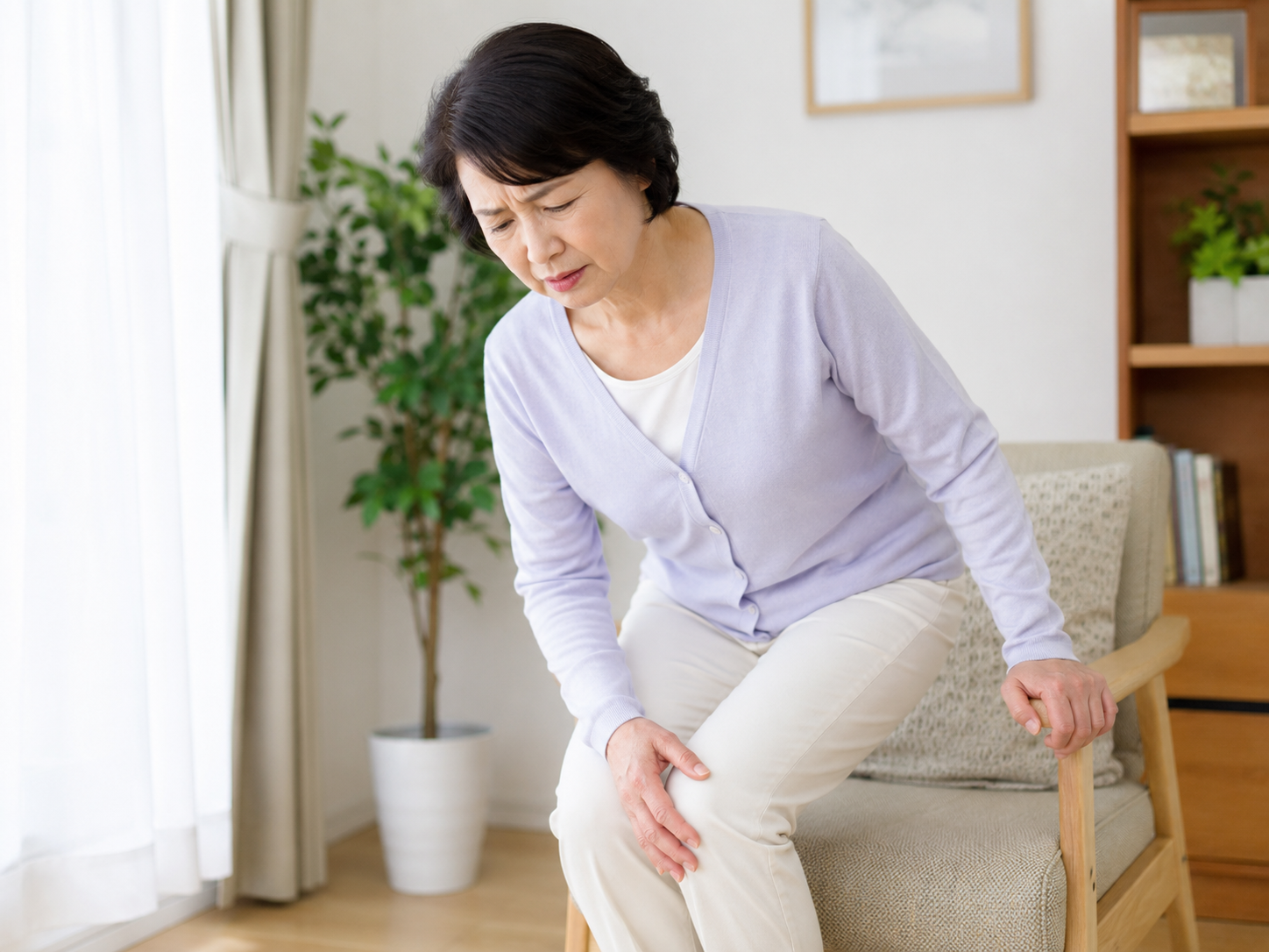 椅子から立ち上がるときに膝を気にしている女性