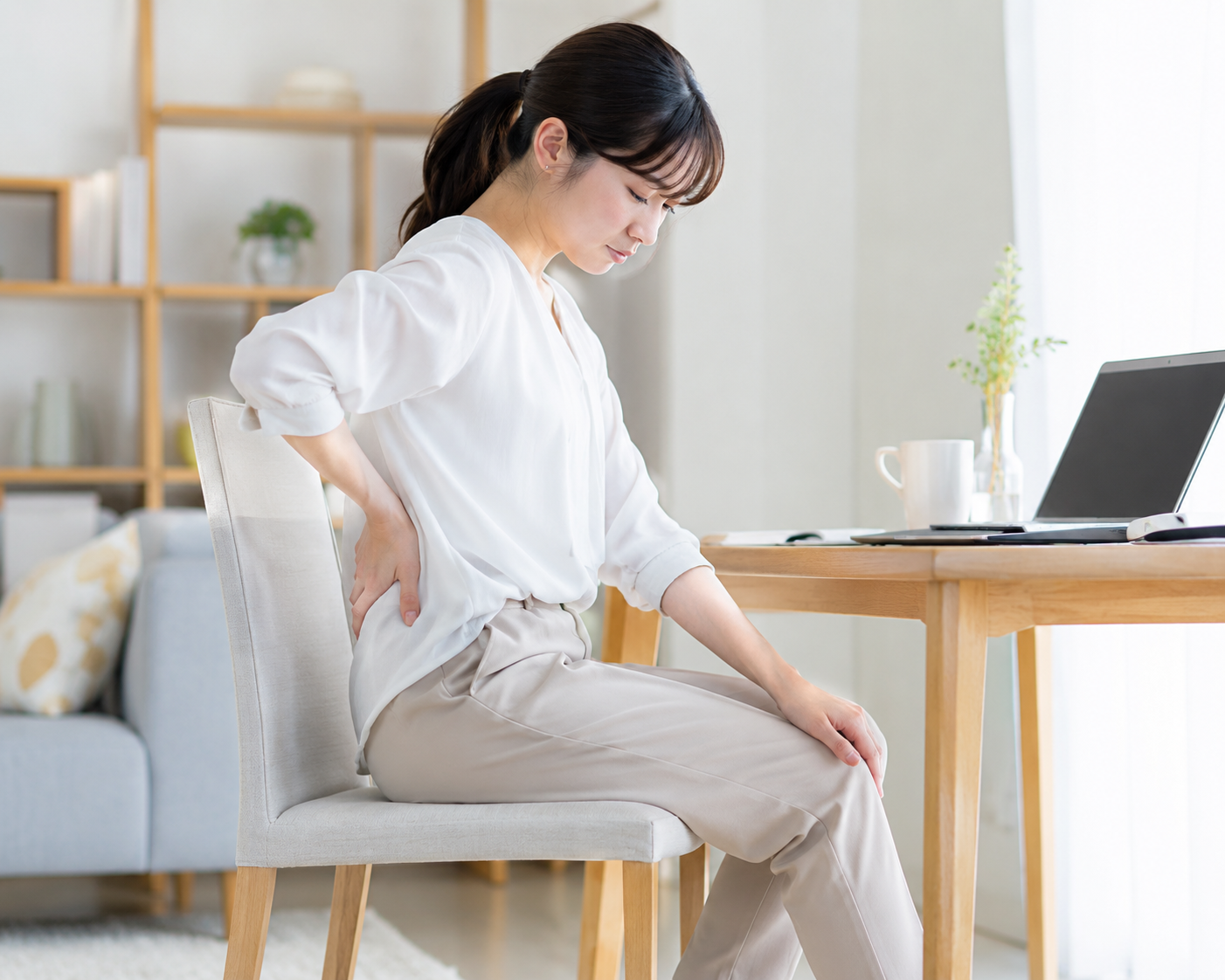 座りっぱなしで腰や足の重さを感じている女性