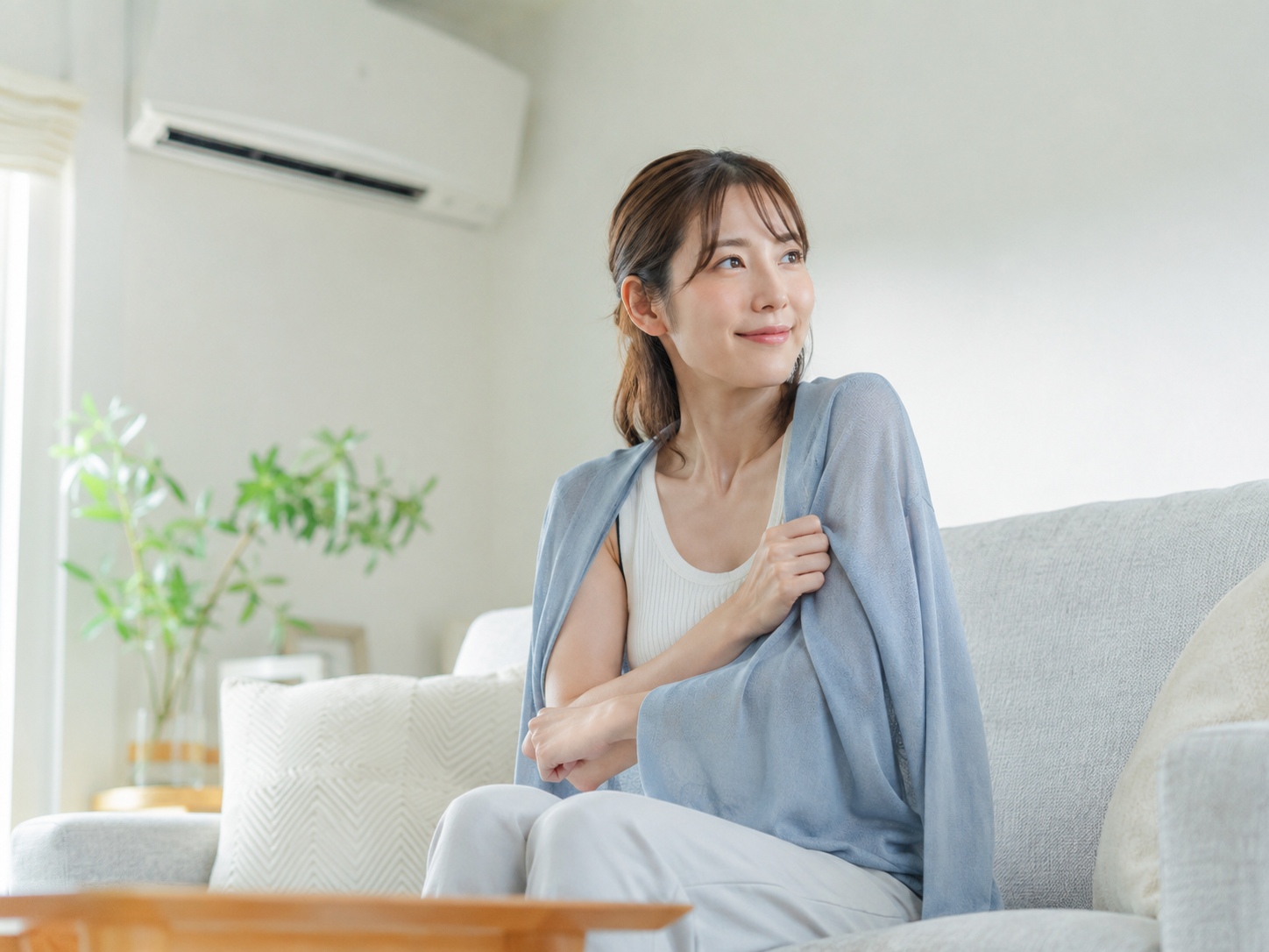 冷房による冷え対策で薄い羽織りものを使う女性