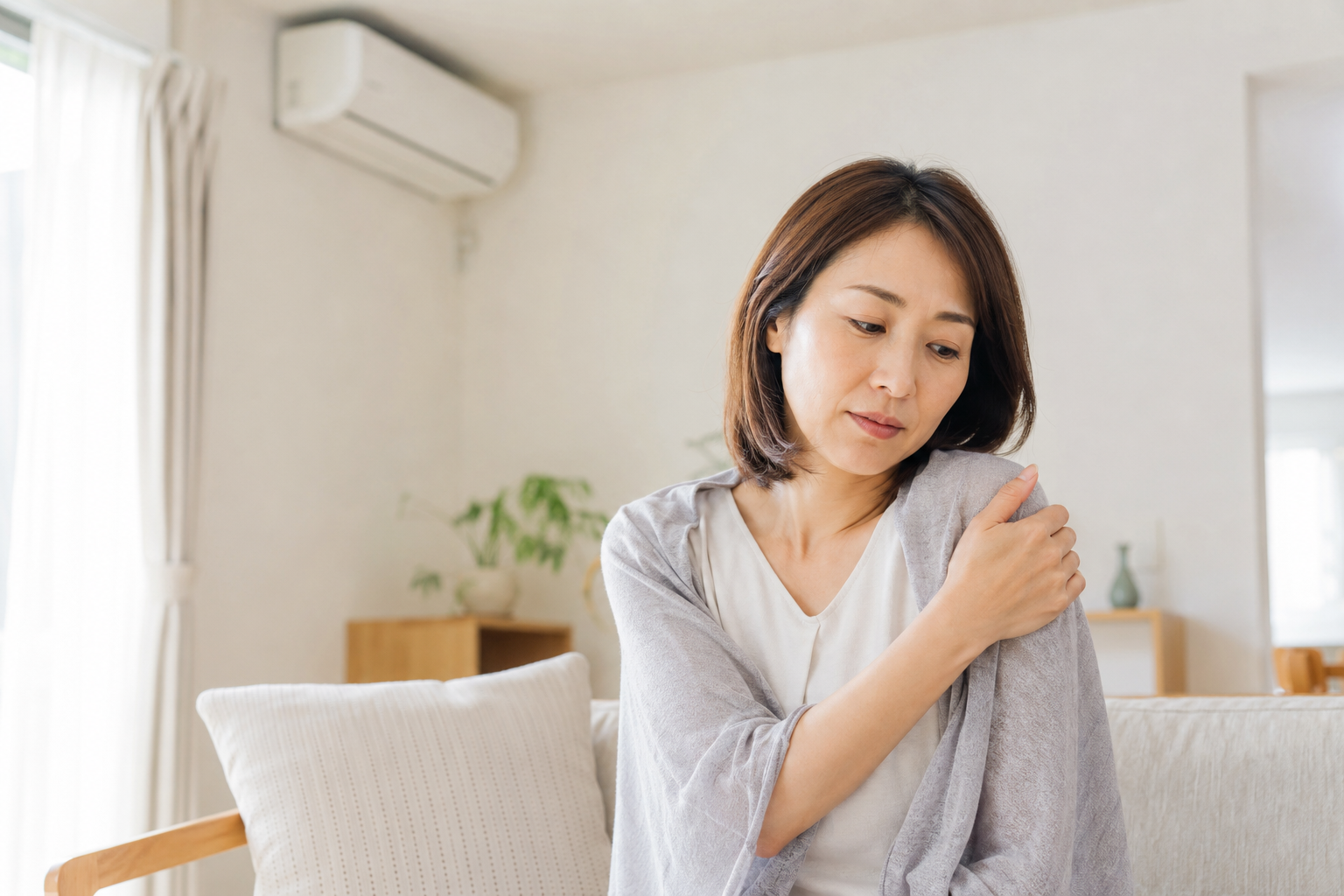 冷房の効いた室内で肩こりを感じている女性