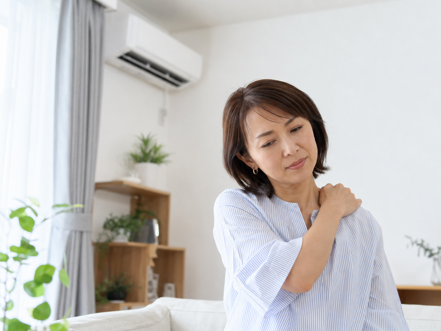 冷房の効いた室内で肩こりを感じている女性