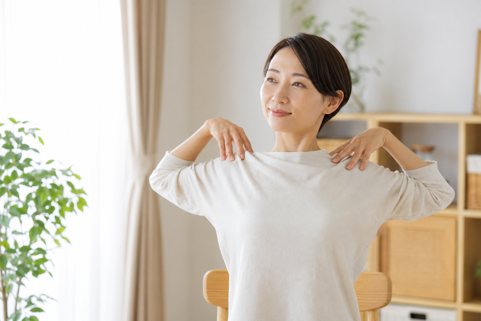冷房による肩こり対策としてやさしく肩を回す女性