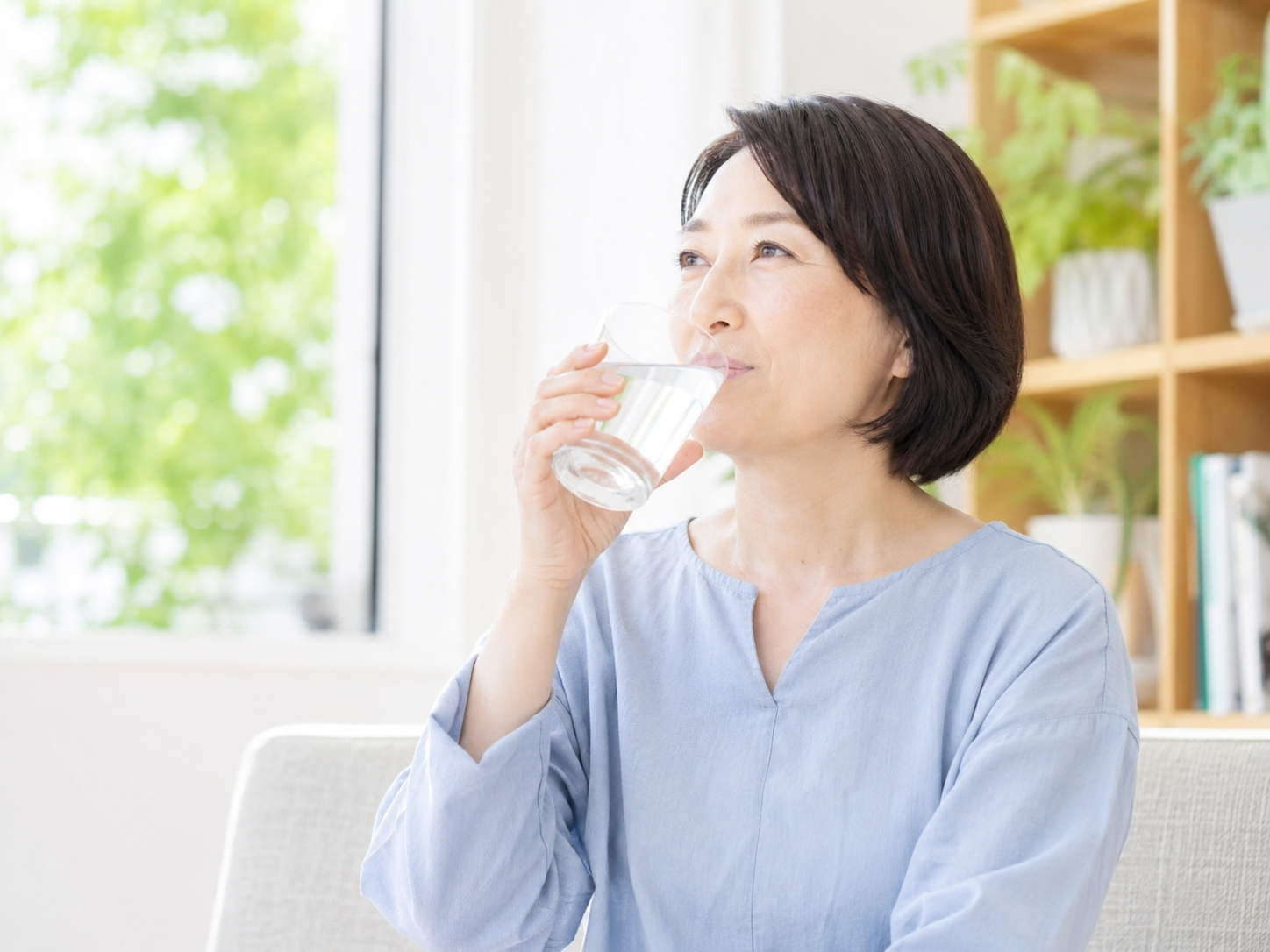 夏の体調管理として高齢女性が室内で水分補給をしている写真