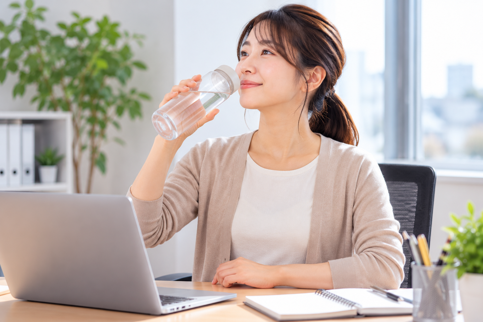 デスクワークの合間に水分補給をしている女性