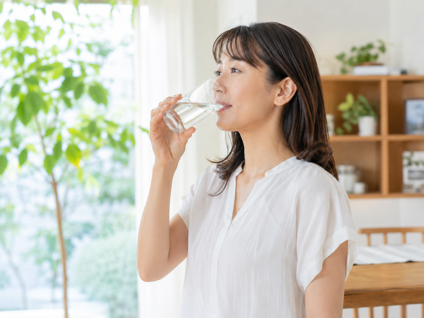 夏の体調管理として室内で水分補給をしている女性