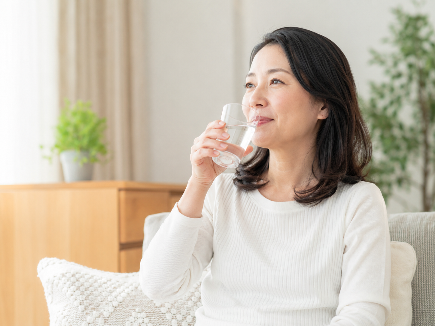 夏前の体調管理として室内で水分補給をしている女性