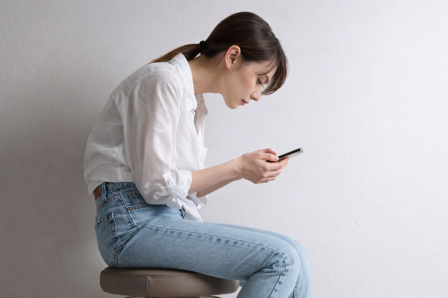スマートフォンを見て首が前に出ている姿勢のイメージ