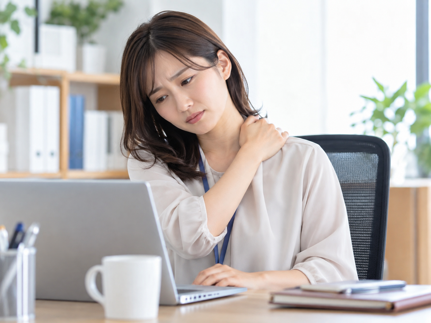 デスクワーク中に首こりや肩こりを感じている女性