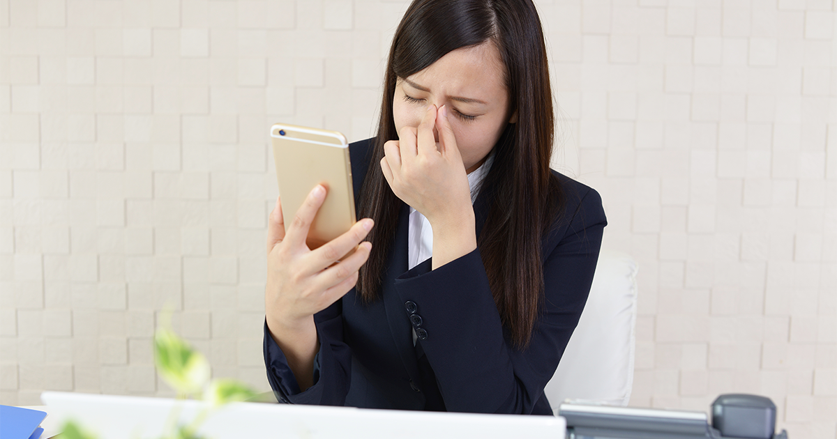スマホを見見続けて目が疲れている女性の写真です。