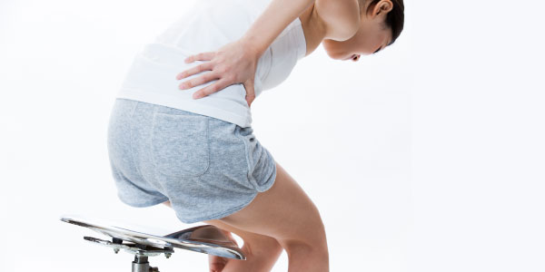 椅子から立ち上がるとき腰の痛みを訴えている女性の写真です。