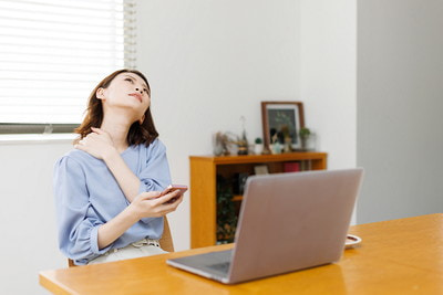 デスクワークで肩がガチガチに固まってつらい女性の写真です。