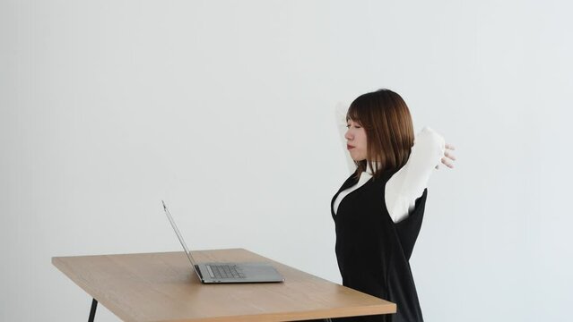 女性が椅子に座って肩甲骨を動かしている写真です。