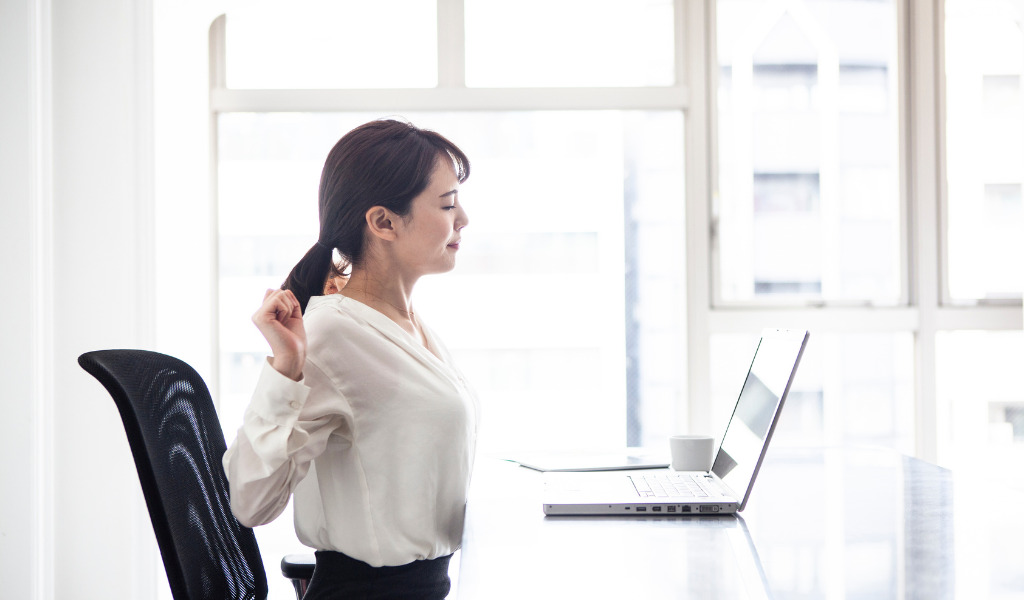 仕事の途中、胸を開くストレッチをしている女性の写真です。
