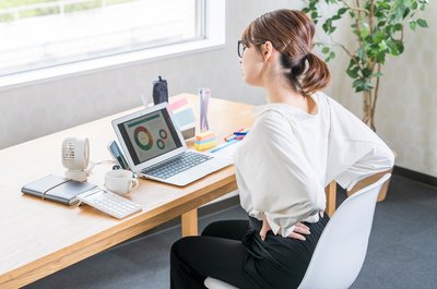 椎間関節性腰痛でデスクワークがつらい女性の写真です。