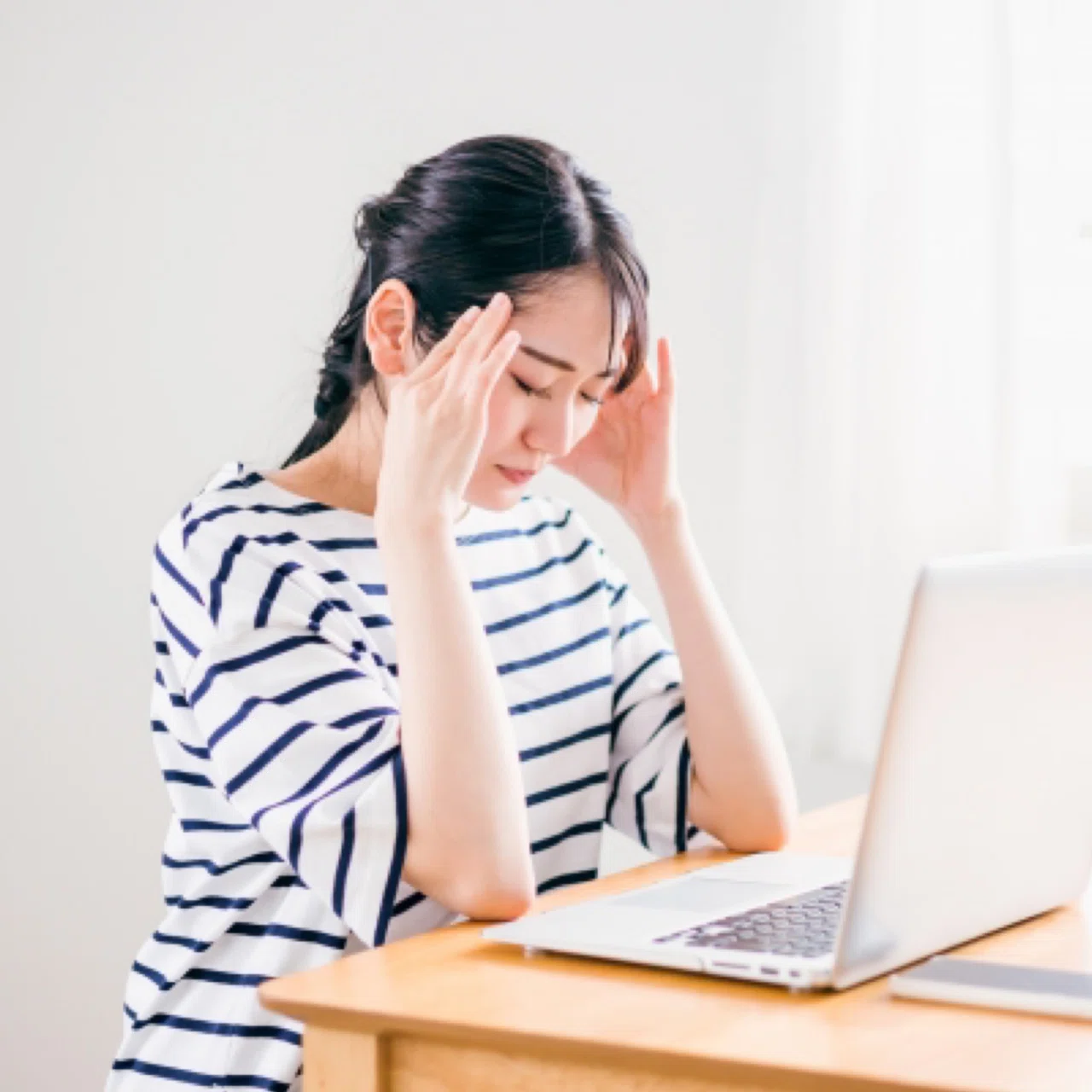 肩こりで頭痛・めまいなどでつらい女性の写真です。仕事に集中できません。